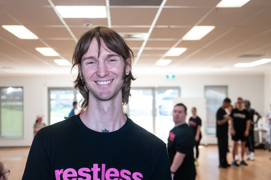 Young man with longish hair smiles at camera