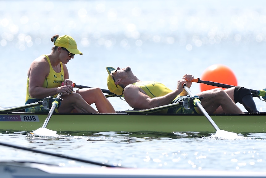 A pair of Olympic rowers on the water. One lies back and yells in triumph.