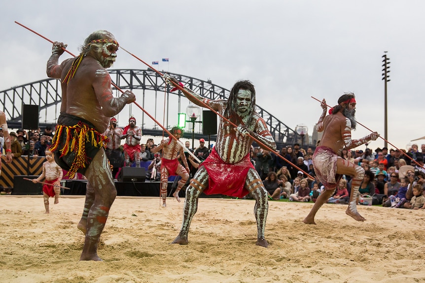 Aboriginal dancers lunging forward with spears.