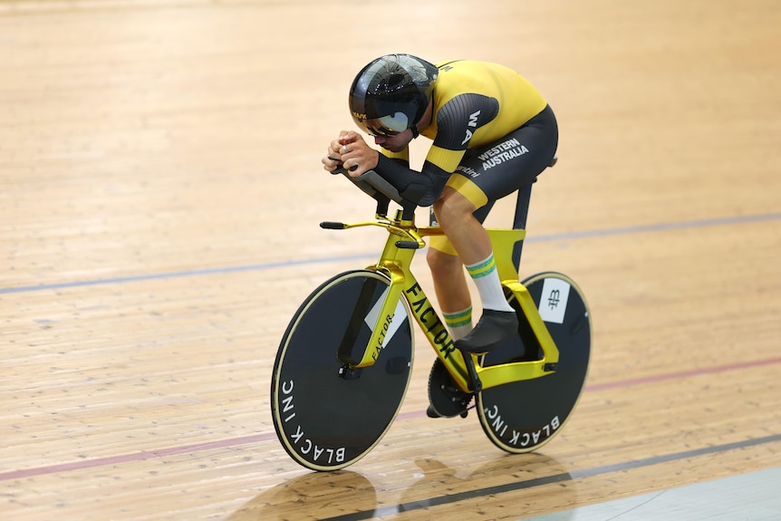 Conor Leahy rides a gold bike in time trial position 
