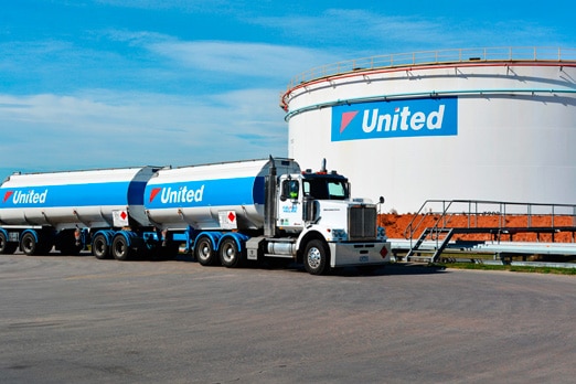 A United Petroleum b-double tanker beside a large storage tank. 