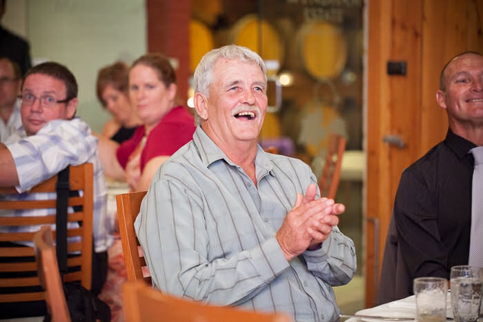 A older man laughing and clapping his hands