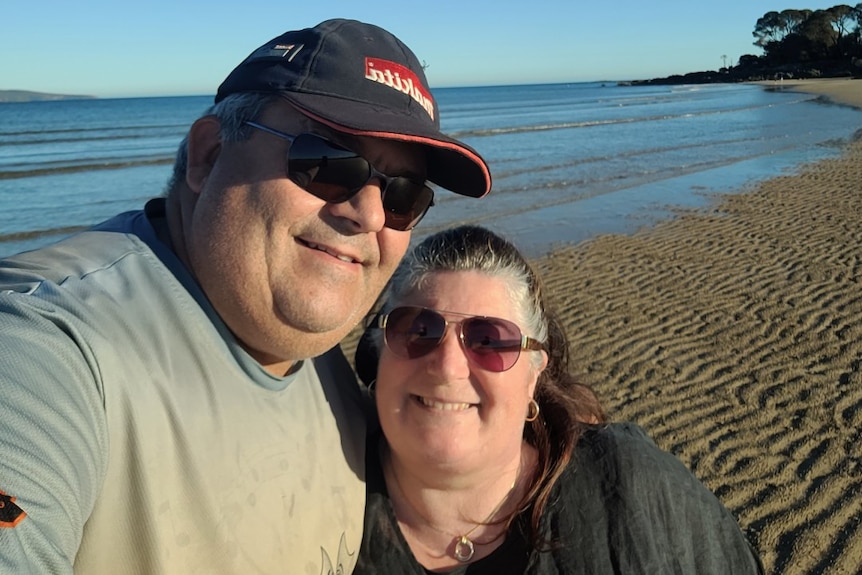 A man and a woman standing at the beach hugging each other. 
