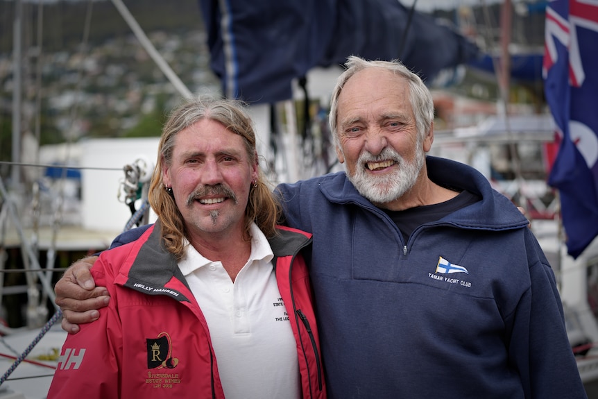 Two men hugging in front of a boat.