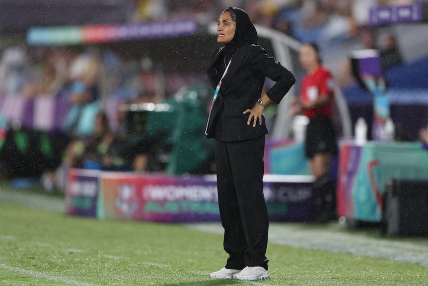 Coach of the Iran women's football team Marziyeh Jafari stands on the sidelines with hands on hips