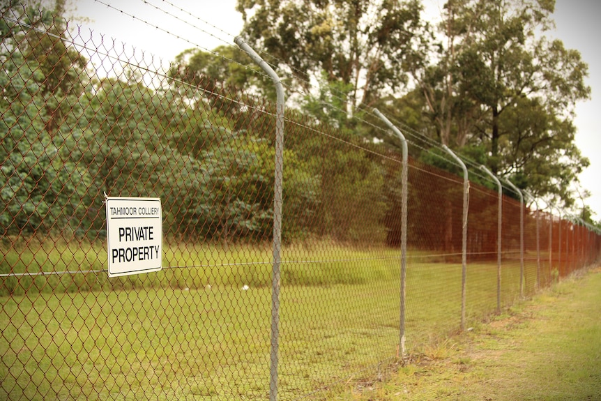 a wire fence with a sign saying Tahmoor Colliery private property