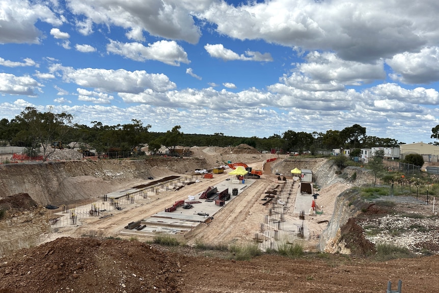 A landscape scene with a large rectangle construction hole cut with steel rod foundations sticking out 