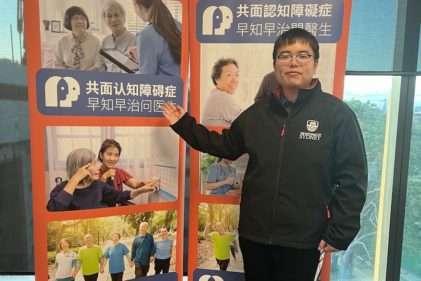 A young man standing in front of a sign.