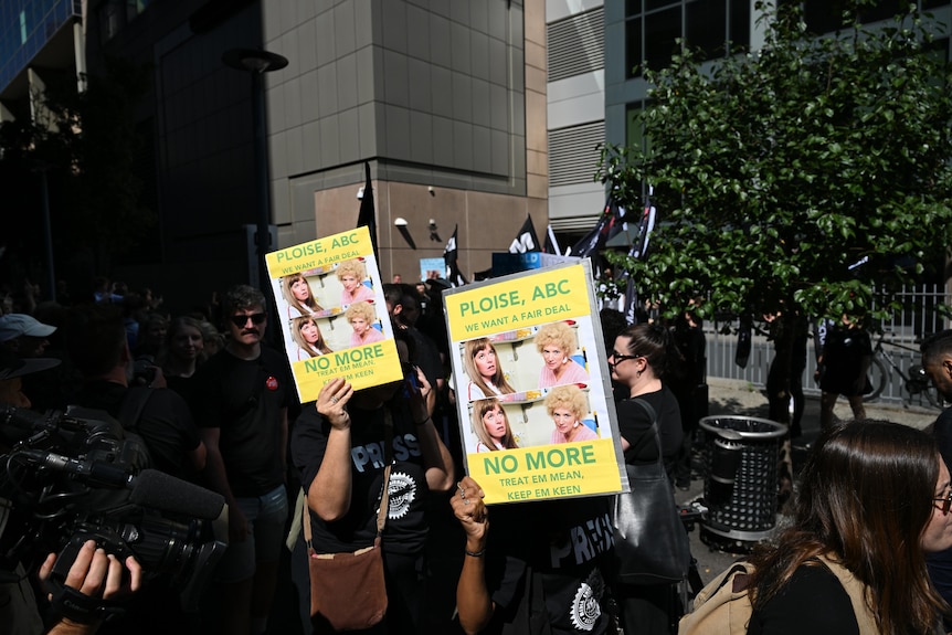 Two yellow signs held up by unidentified people with Kath and Kim saying "Ploise, ABC we want a fair deal"