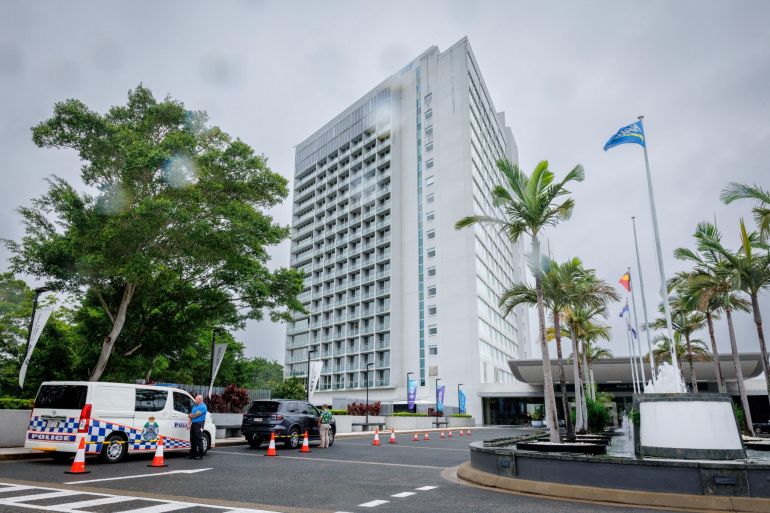 A hotel security member stands beside a police van (L) at the entrance to the Royal Pines Resort, where members of the Iranian womens football team are staying, on the Gold Coast on March 9, 2026. Australia must protect the visiting Iranian women's football team, the son of the nation's late shah urged March 9, warning their refusal to sing the national anthem before a match could have "dire consequences". (Photo by Patrick HAMILTON / AFP)