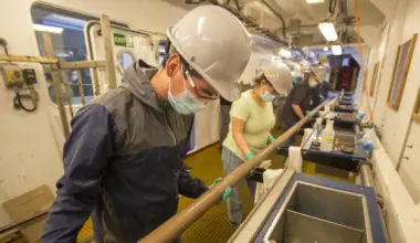 Above left, Oscar Cavazos (Marine Laboratory Specialist, IODP JRSO) joins other marine techs in preparing the core new to be sectioned on the catwalk. Photo Credit: Erick Bravo, IODP JRSO