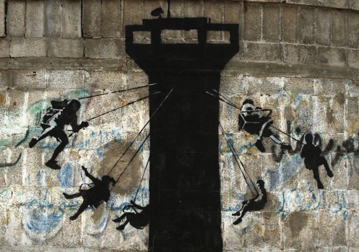 Children swinging from an Israeli watch tower by Banksy