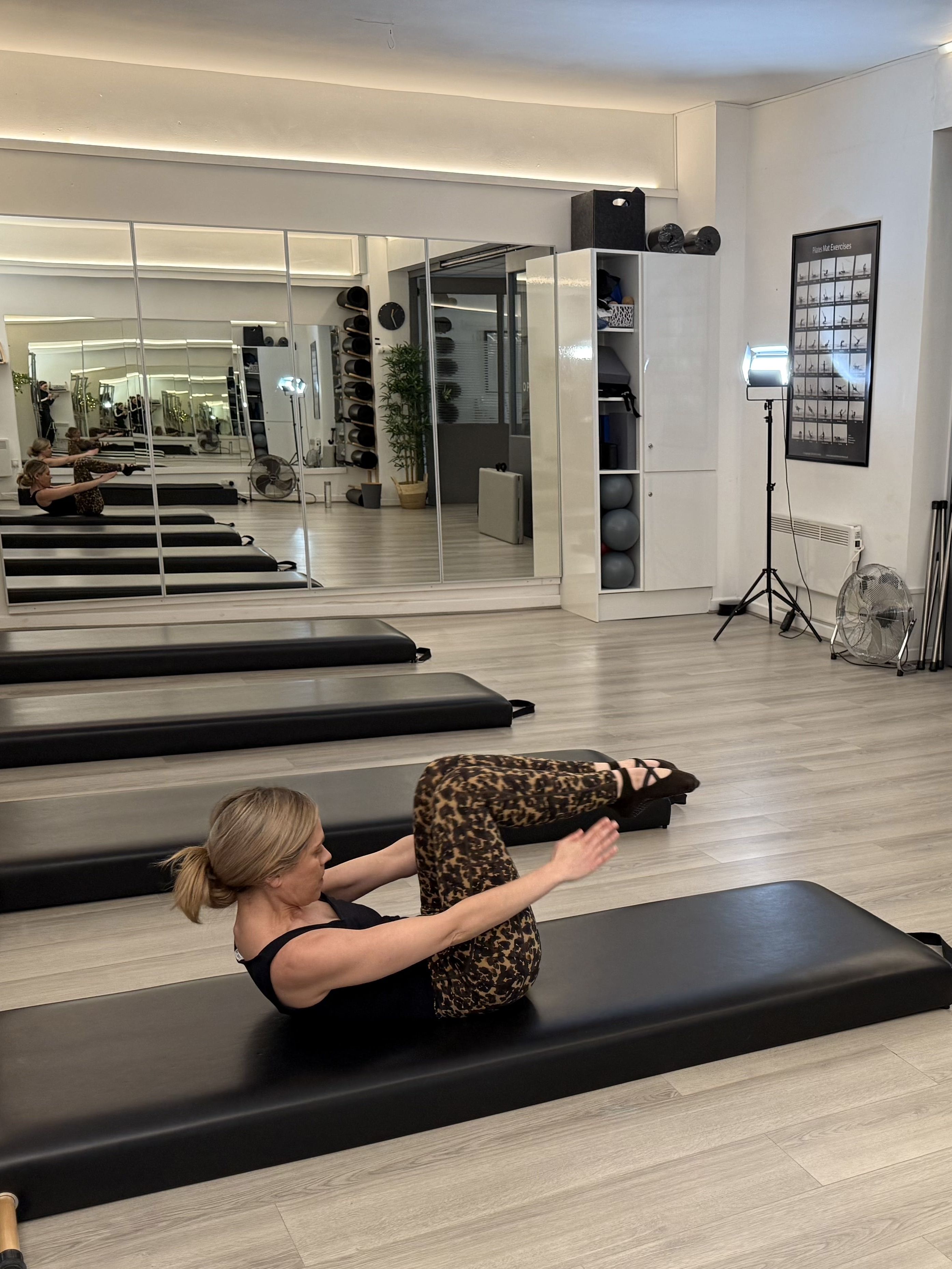 Woman demonstrating a Pilates movement in a studio setting
