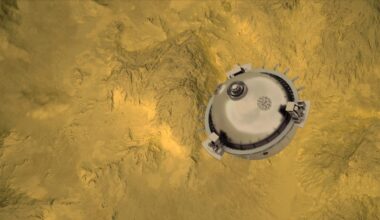 a silver spherical probe above a yellow-and-grey mountainous landscape, as seen from far above