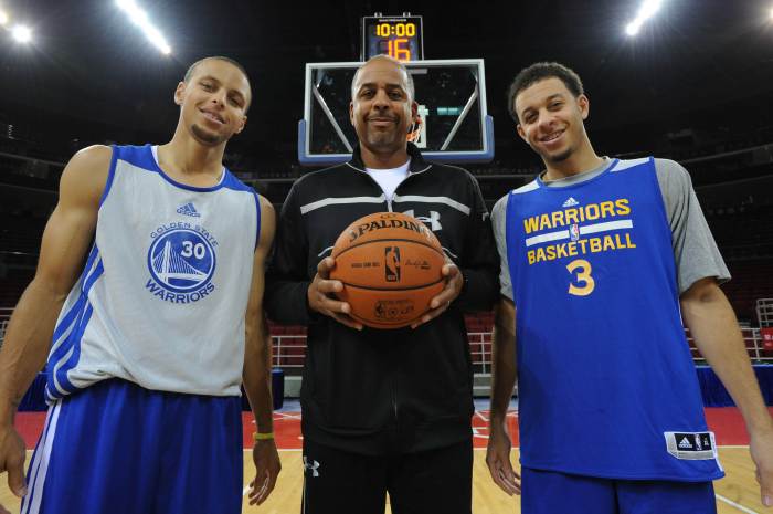 Stephen Curry #30, Dell Curry and Seth Curry pose for a photo on the court.