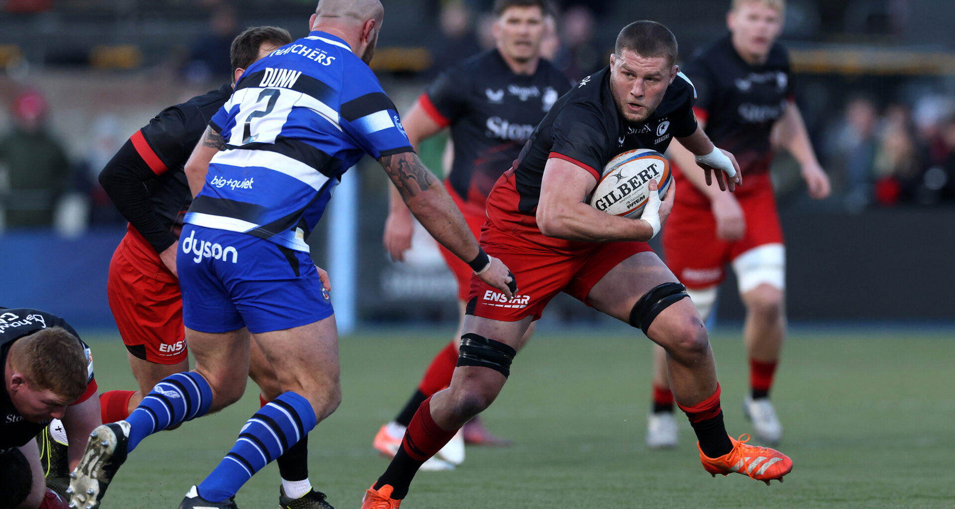 Tom Willis of Saracens runs with the ball as Bath's Tom Dunn prepares to make a challenge in the Gallagher PREM match in November 2025