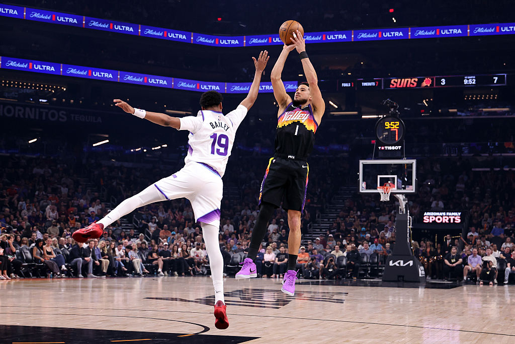 PHOENIX, ARIZONA - MARCH 28: Devin Booker #1 of the Phoenix Suns shoots the ball against Ace Bailey...