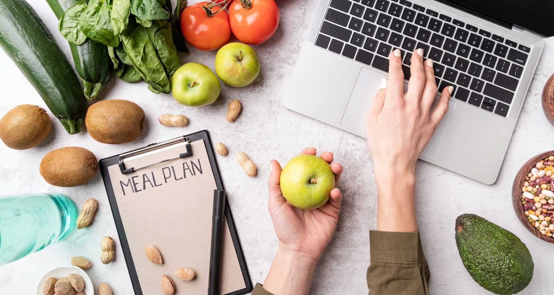 Woman workspace with healthy food. Female hands writing in the notepad words