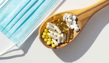 Closeup of probiotic tablets on wooden spoon next to face masks. Concept of supplementation during the pandemic.