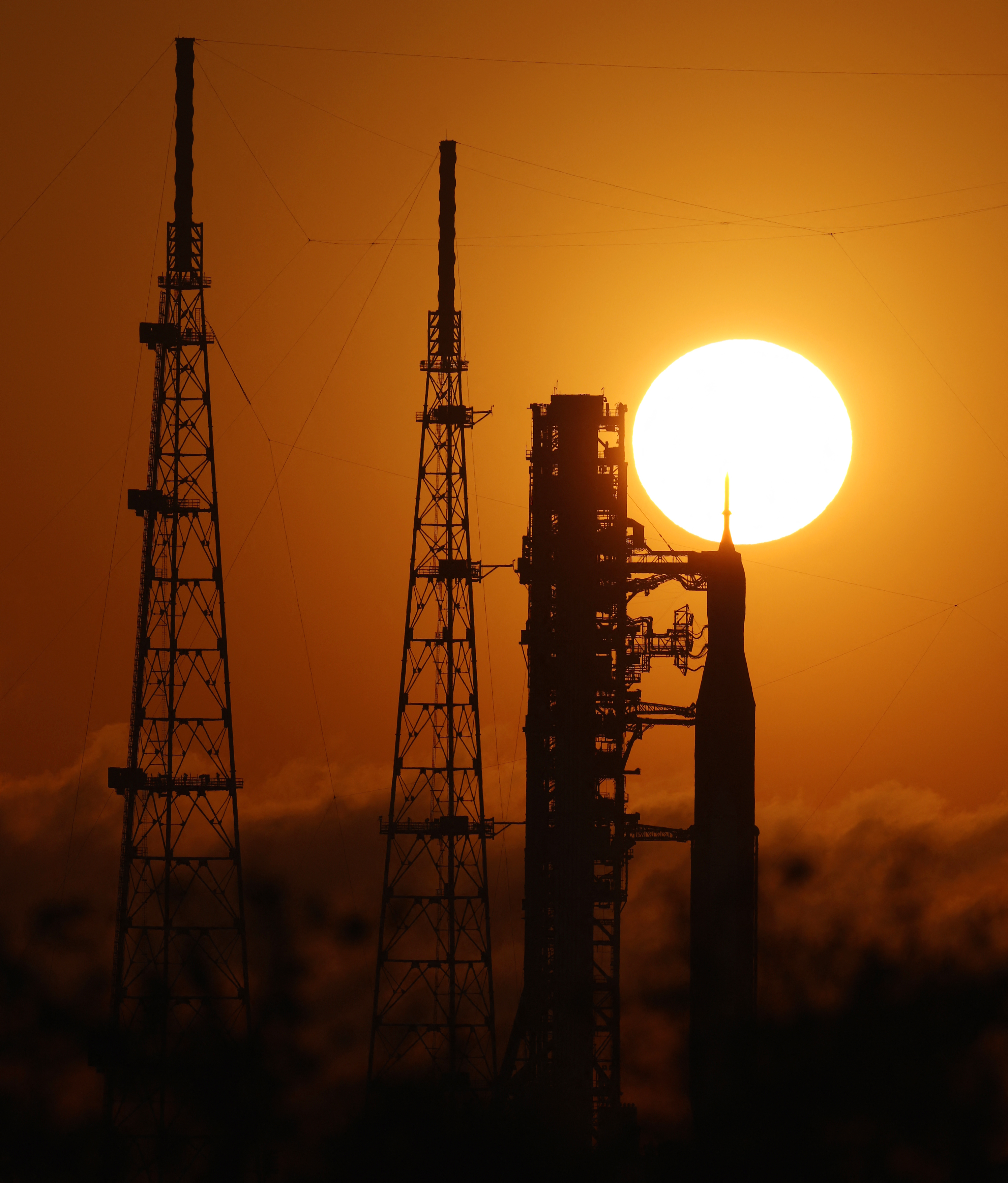 A rocket is stands in silhouette in front of a sunset.