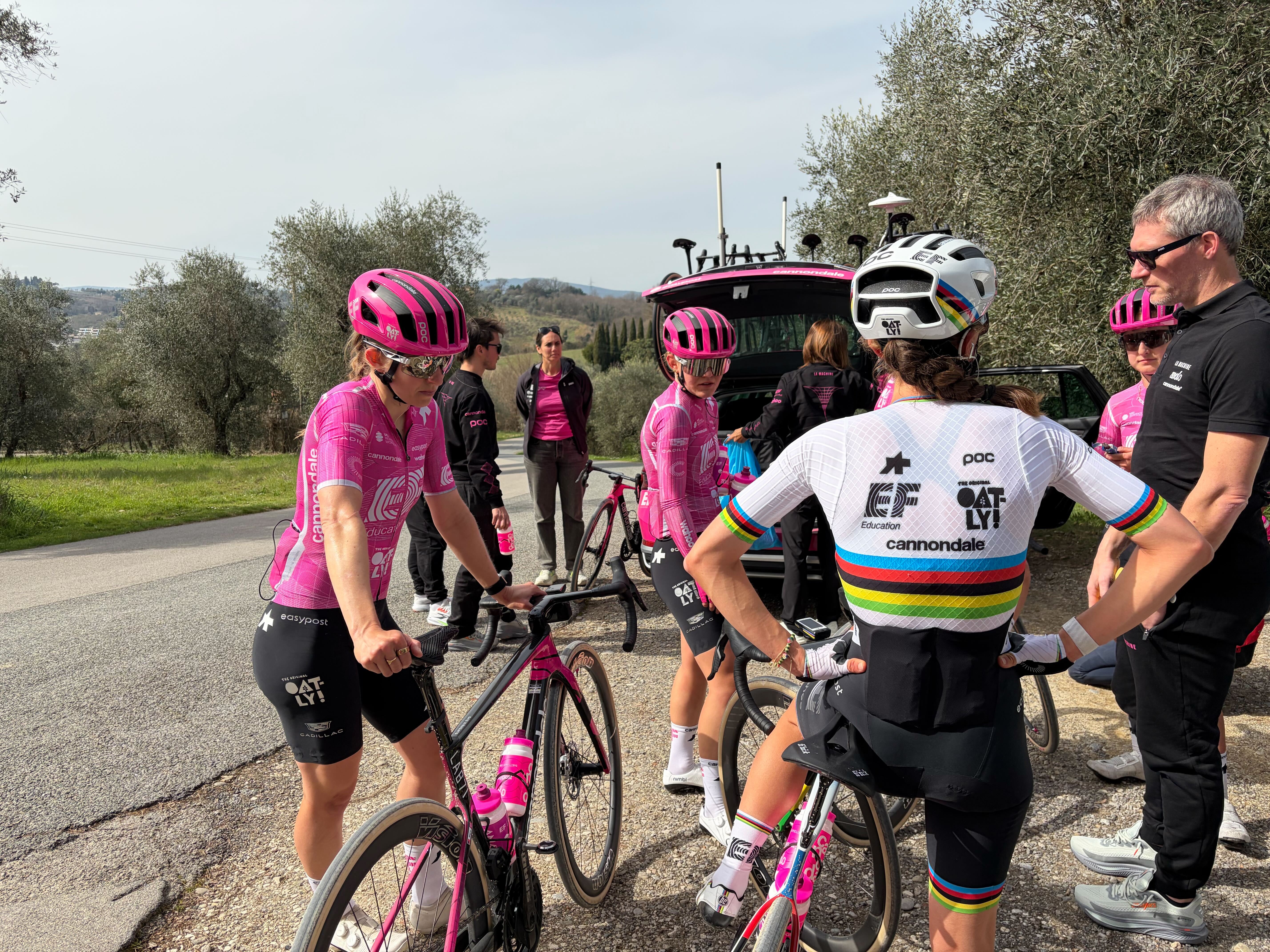 World champion Magdeleine Vallieres with her back to the camera as a group stand behind the team car