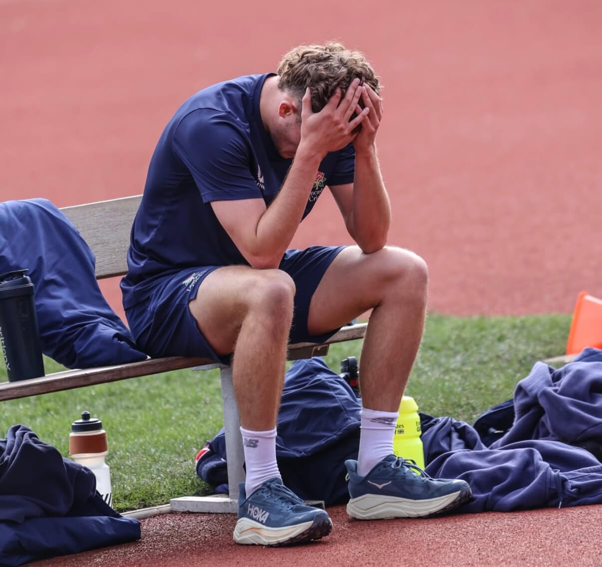 Charlie Barnard, head in hands, sits on a bench to recover from his run