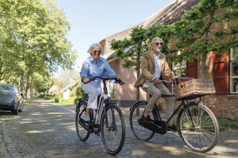 Beautiful senior travelling tourist couple enjoying a spring day whilst biking on holiday in a cosy dutch village