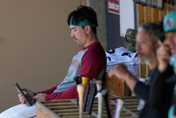 Injured Arizona Diamondbacks' Corbin Carroll sits in the dugout during the second inning of a spring training baseball game against the Los Angeles Dodgers Wednesday, Feb. 25, 2026, in Scottsdale, Ariz. (AP Photo/Ross D. Franklin)