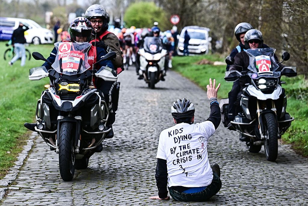A protestor sits on the road while riders compete in the 'Ronde van Brugge' men's elite one-day cycling race, 202,9 km from and to Bruges on March 25, 2026. (Photo by MAARTEN STRAETEMANS / Belga / AFP) / Belgium OUT