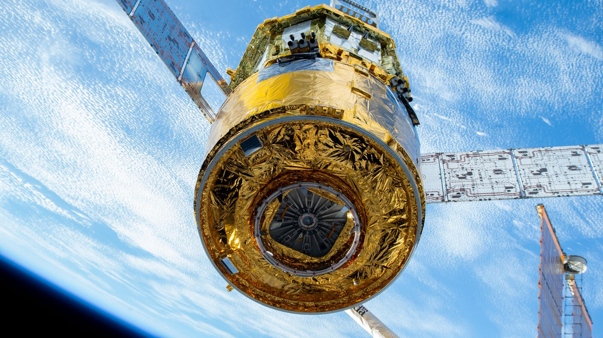closeup of a golden cylindrical spacecraft with earth in the background