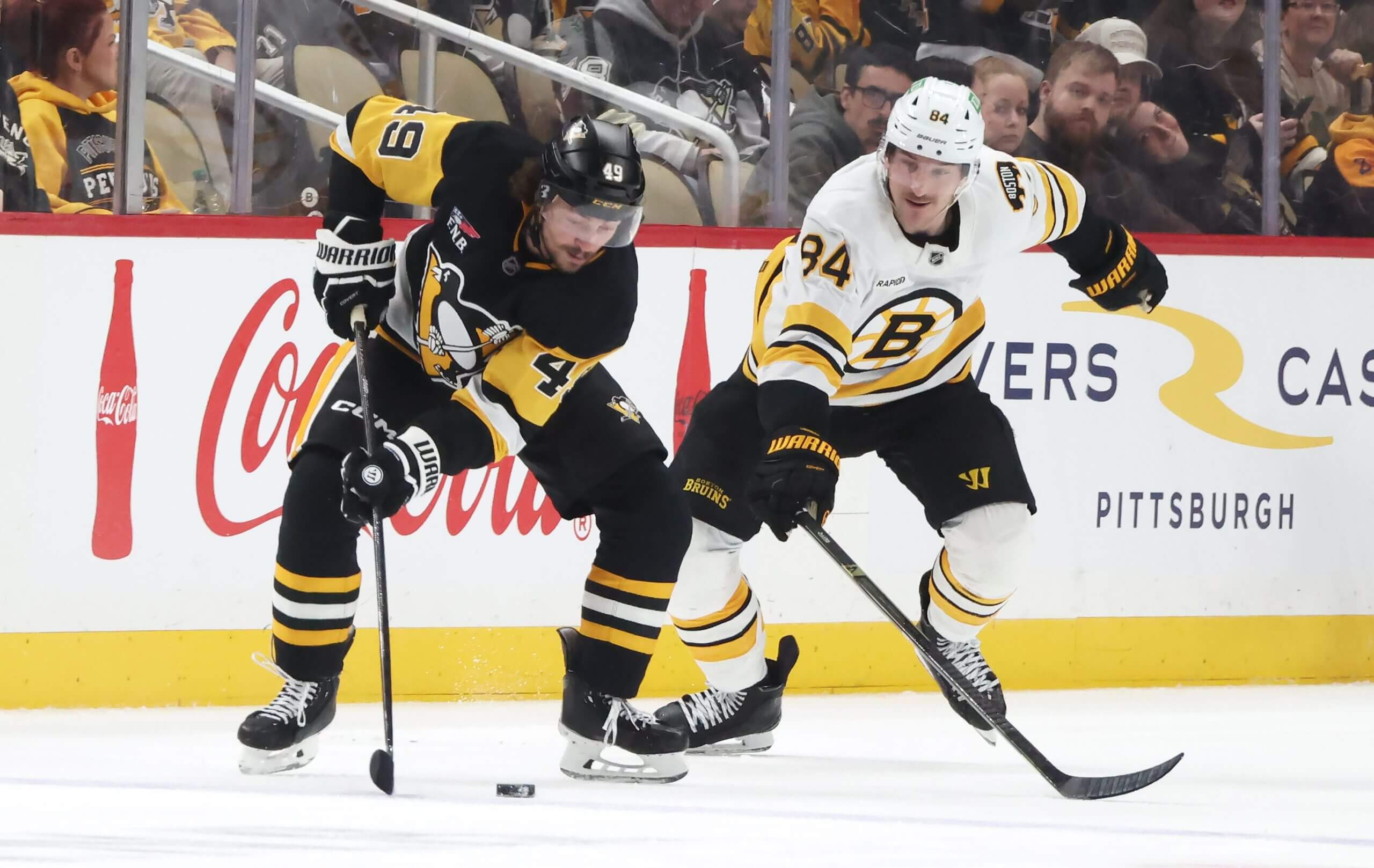 Sam Girard controls the puck with a Bruins player skating in to defend.