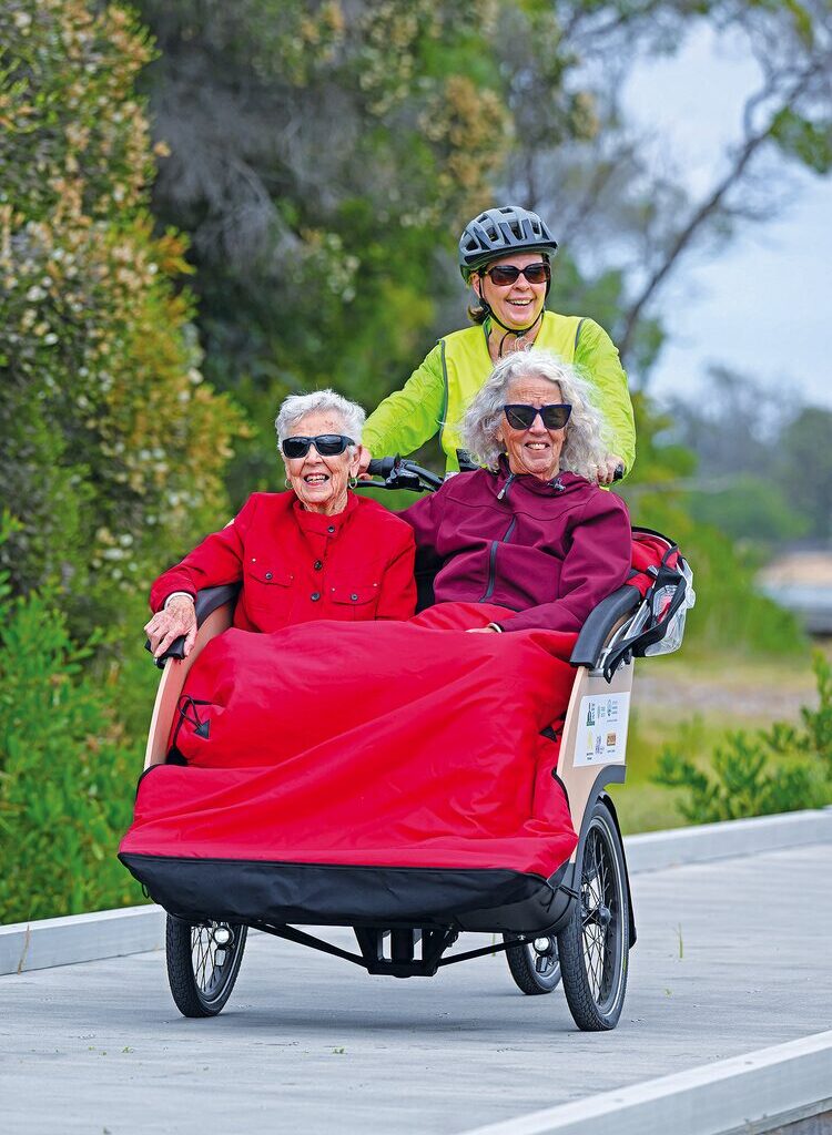Joyce Grimer, 98, enjoys a Lakes Entrance esplanade ride with her daughter Pam Waters, piloted by volunteer Julie Chester, marking CWAG's oldest passenger to date. (PS)