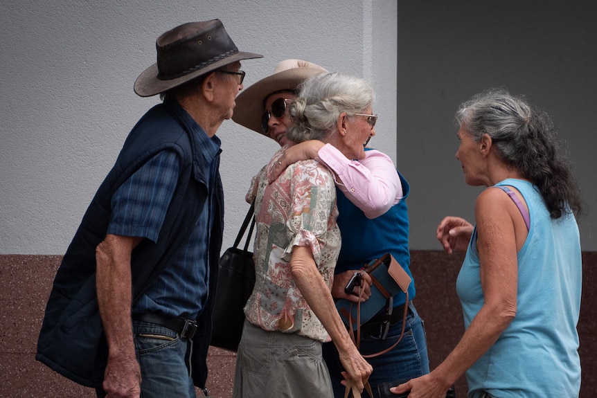 A group of elderly people hug 