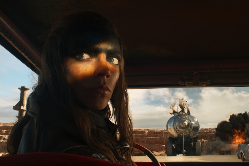Anya Taylor-Joy sits in a car looking out in a scene from movie Furiosa A Mad Max Saga