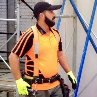 Ghanim wears a high-visibility shirt and a cap at a worksite.