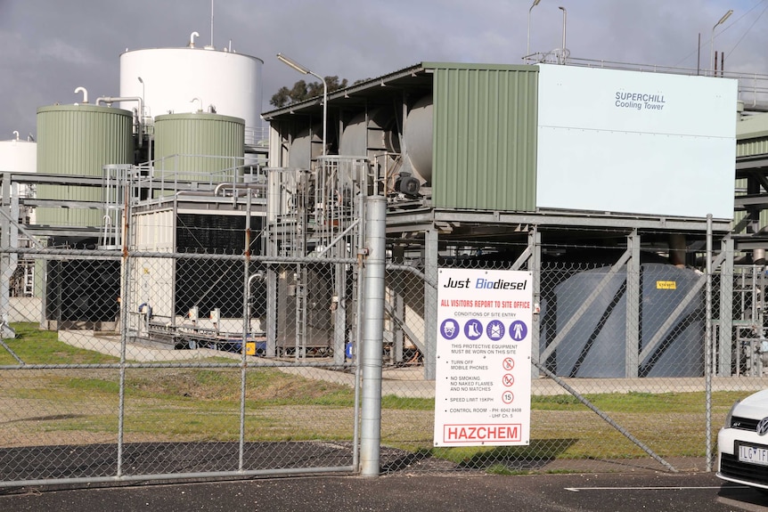 A sign outside of a wire fence at a factory.