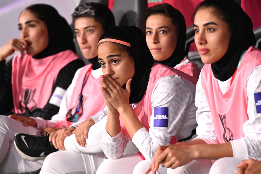Members of the Iranian women's football team watch on the bench during a game