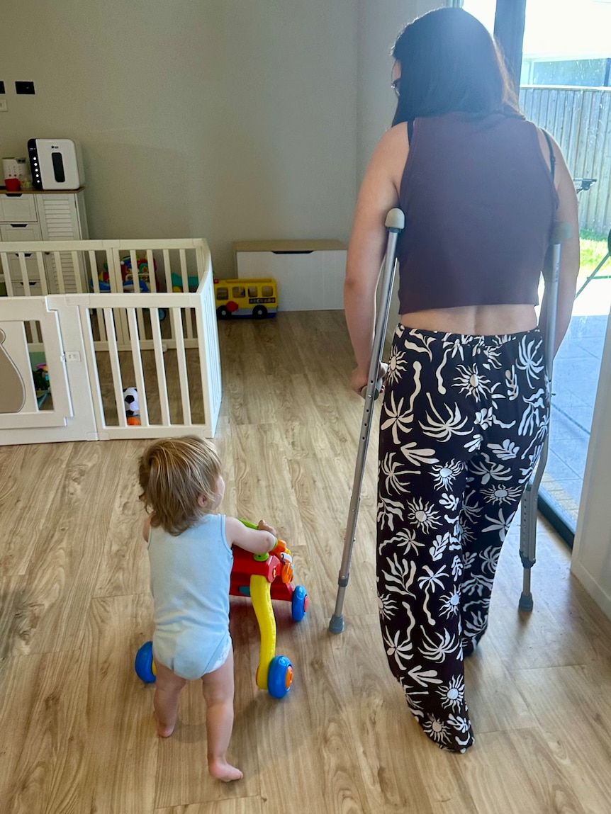 A woman on crutches walking next to her son