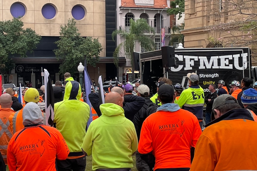 a large group of workers in high-vis shirts gathered at a park. CFMEU branding can be seen in the background