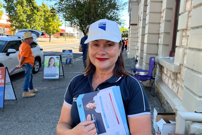 A woman holding how to vote cards looking at the camera. 