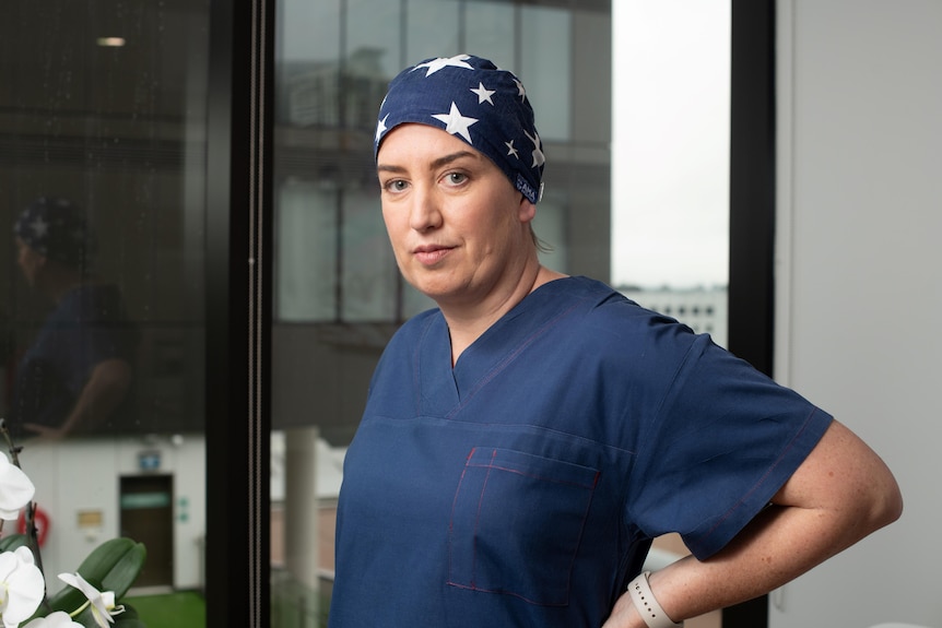 Woman in blue hospital scrubs and head scarf