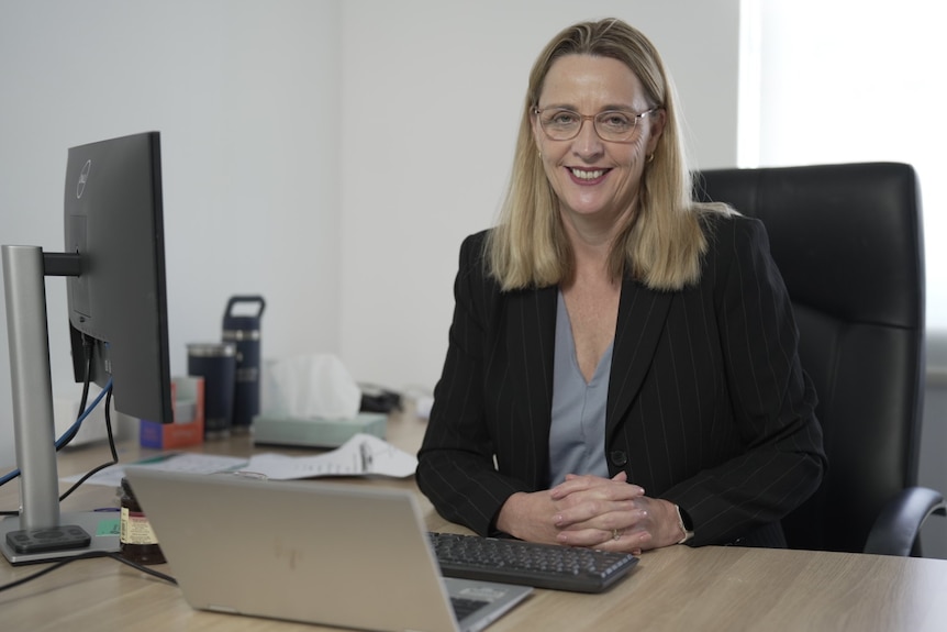 A woman with blond hair and glasses in her office in Sydney.
