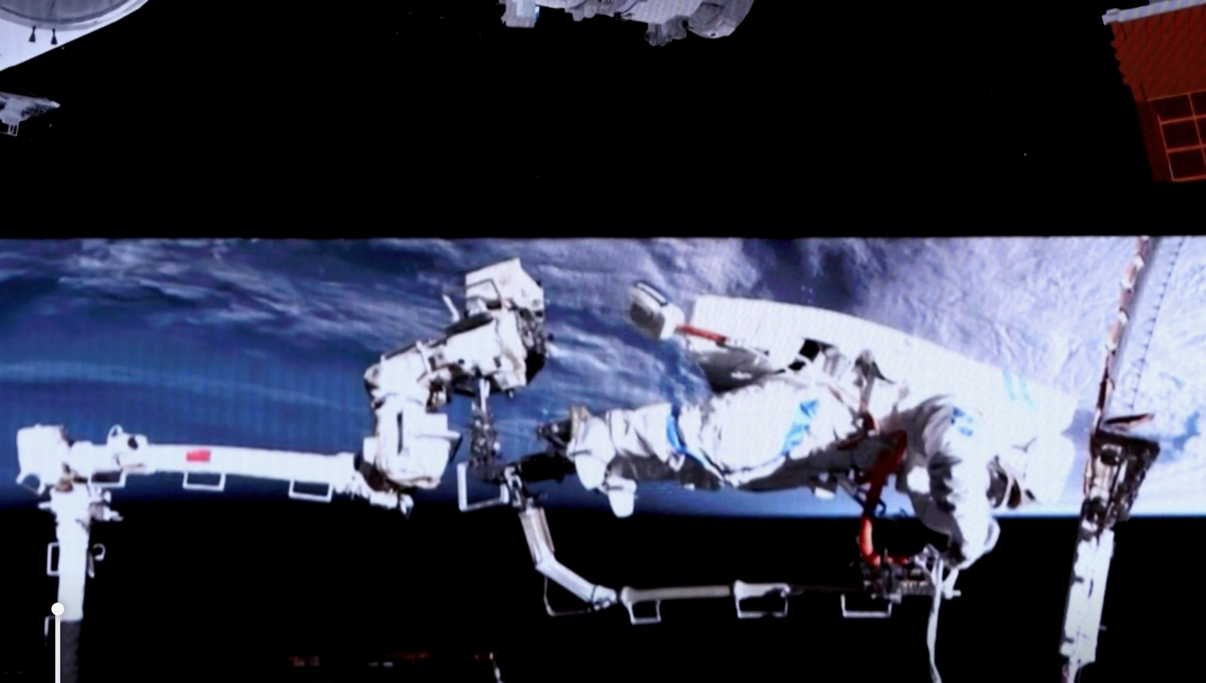 an astronaut in a white spacesuit conducts a spacewalk outside a space station, with earth in the background
