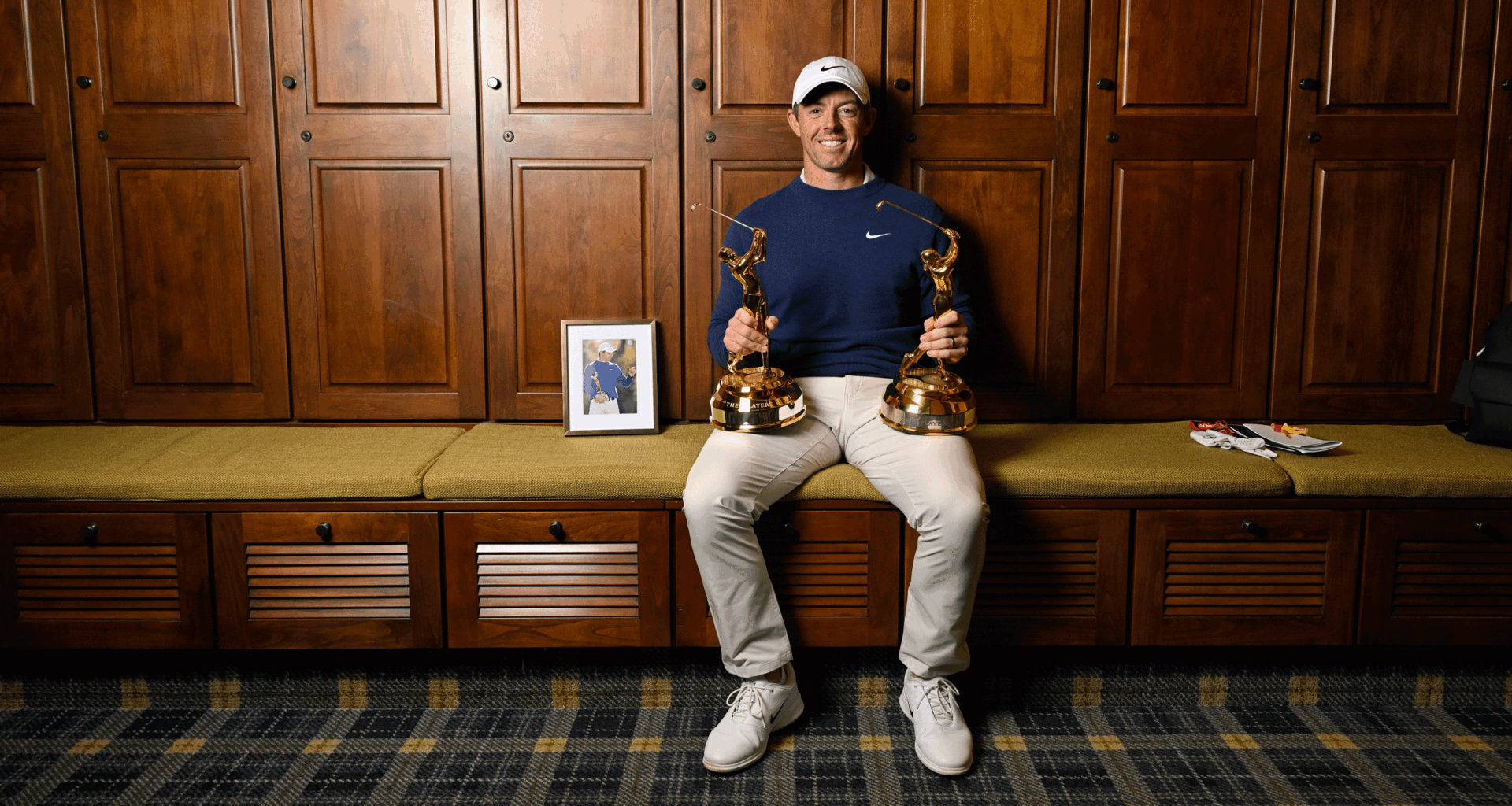 Rory McIlroy sits in the locker room at TPC Sawgrass with his two Players Championship trophies resting on his legs