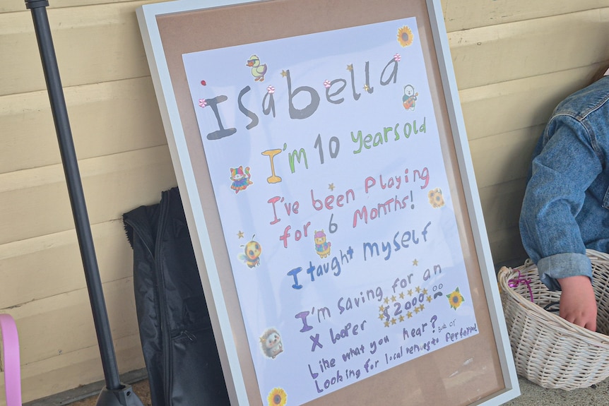 A board lays against a wall telling the story of Isabella who is basking after teaching herself to play music six months ago. 