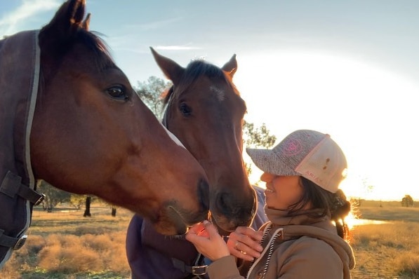 A woman feeding two horses 