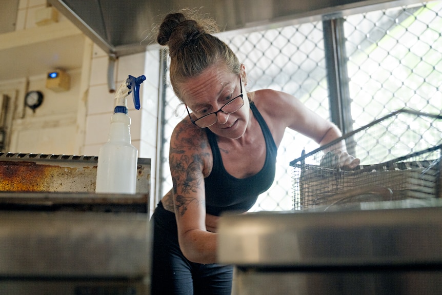A woman cleans a kitchen in the aftermath of a flood.