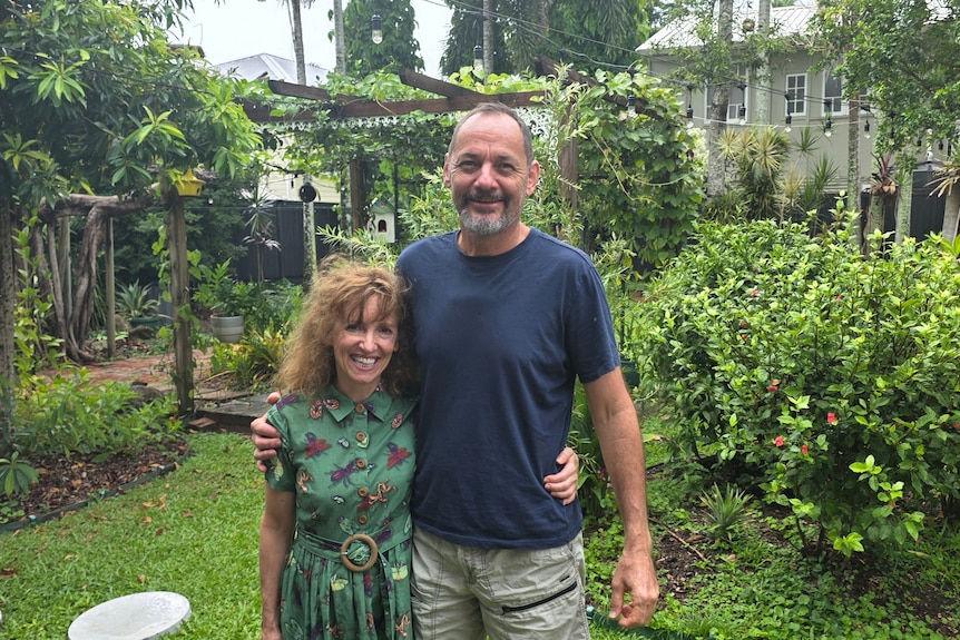 A man and woman hugging in a garden.