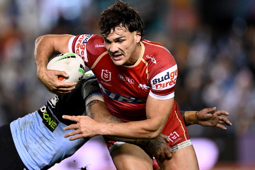 Herbie Farnworth of the Dolphins is tackled by Sione Katoa of the Sharks during the NRL Round 19 match in 2026.