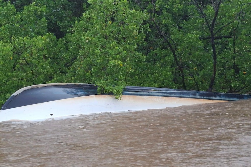 A boat tipped upside down underwater in the Daintree River. 